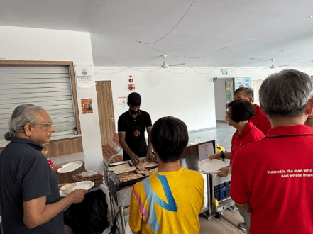 A group of people standing around a table with food
AI-generated content may be incorrect.