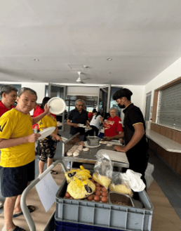 A group of people standing around a table with food
AI-generated content may be incorrect.